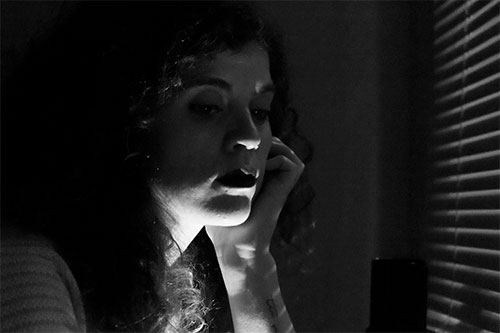 black and white photo of a woman sitting in the dark