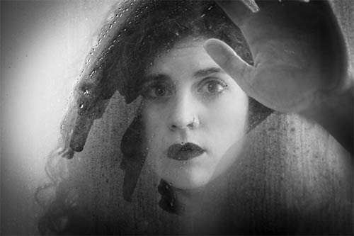 black and white photo of a woman behind a window